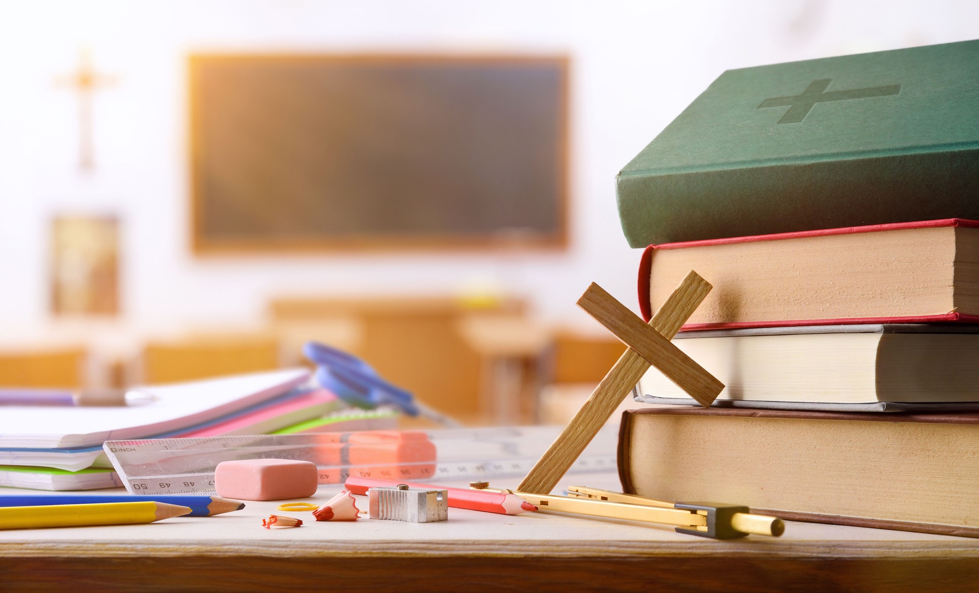 Educational supplies and religious objects on table with classroom background